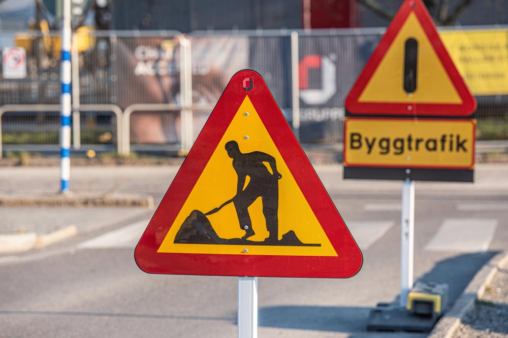 Varningsskyltar för vägarbete med byggtrafik-märke framför stadsgata i Sverige